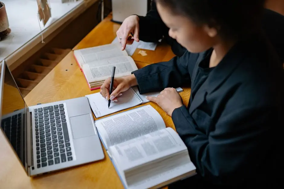 Mahasiswa belajar dengan buku dan laptop di meja rumah
